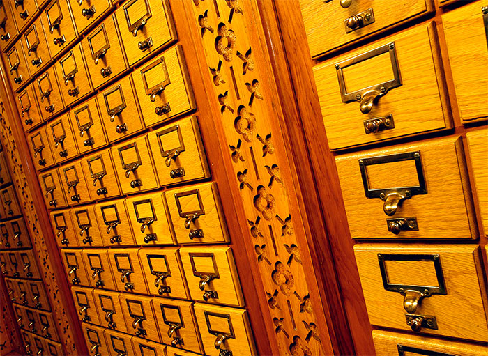 Photo des tiroirs en bois dans lesquels étaient conservées les fiches du catalogue de la Bibliothèque. Ces tiroirs se trouvent dans deux alcôves de la Bibliothèque principale.