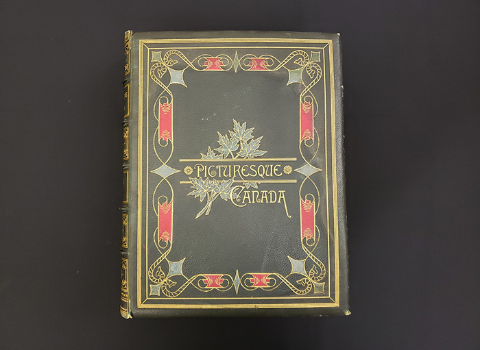 Volume de cuir vert décoré de motif rouge et vert. Un motif de feuille d’érable encadre le titre du livre.