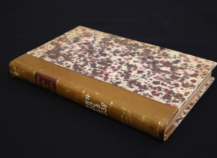 Book with leather spine and marbled paper covers on a black surface
